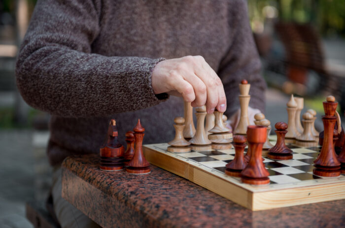 Arm of old man playing chess in park